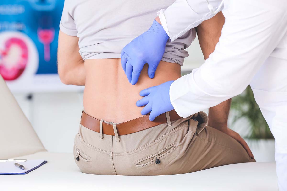 Doctor checking man's lower back to assess kidney function or kidney damage for peritoneal dialysis