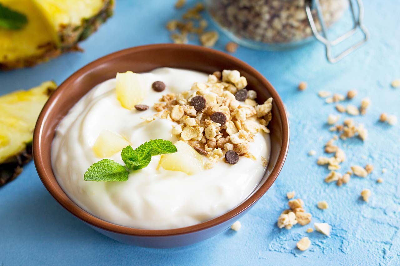 Greek yogurt with pieces fresh pineapple and other toppings. 