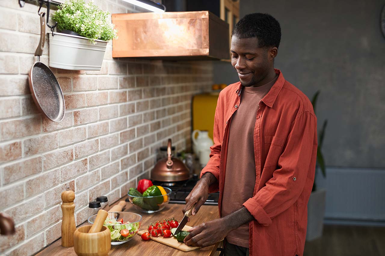 man chopping up fresh vegetables for a salad in his kitchen