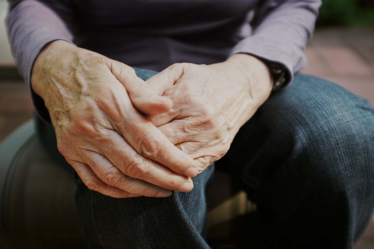 older woman seated with hands on her knee 