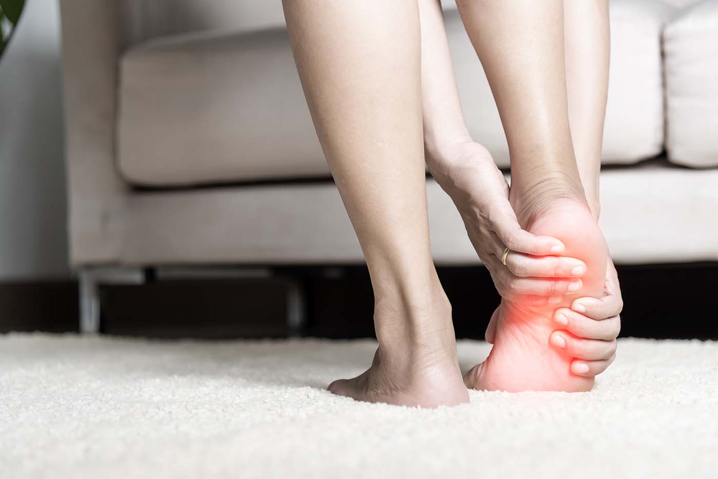 barefoot woman suffering heel pain at home
