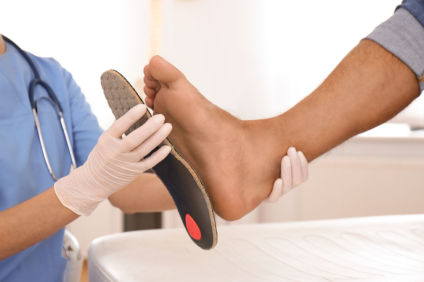 orthopedist fitting insole on patient's foot
