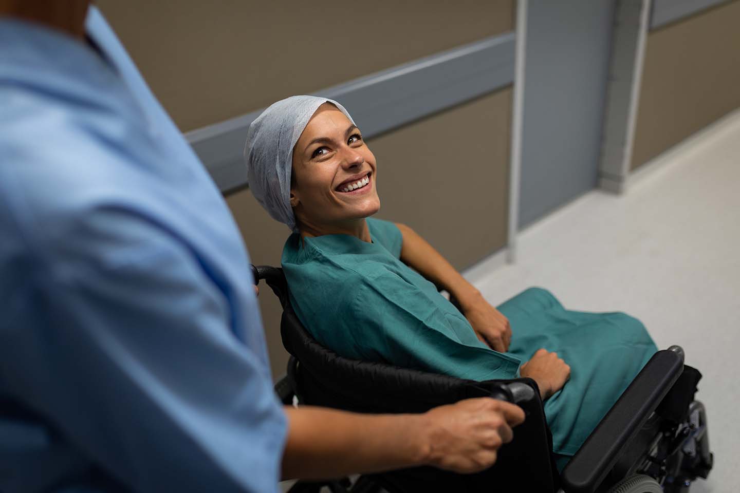 smiling patient being wheeled down a hospital hall
